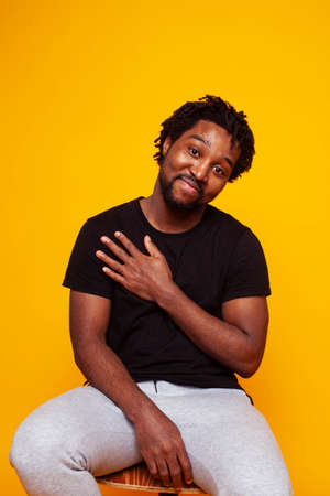 young handsome african american guy student posing cheerful and gesturing on yellow background, lifestyle people conceptの写真素材