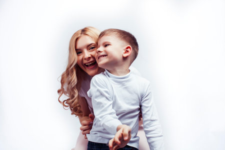 young modern blond curly mother with cute son together happy smiling family posing cheerful on white background, lifestyle people concept, sister and brother friendsの写真素材