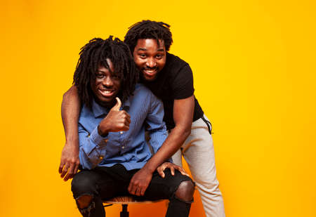 two african american guys posing cheerful together on yellow background, lifestyle people conceptの写真素材