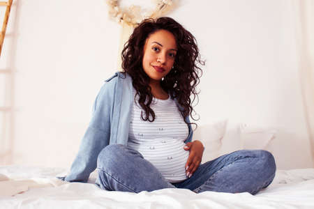 young pretty african american woman pregnant laying in bed, lifestyle people concept
