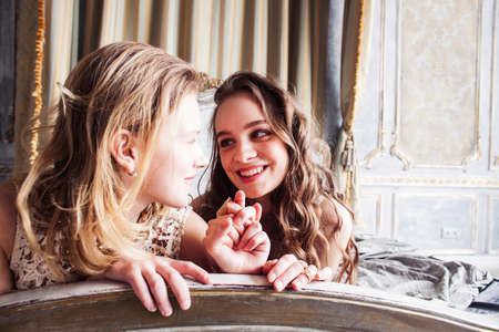 two pretty twin sister blond curly hairstyle girl in luxury house interior together, rich young...