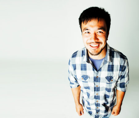 young cute asian man on white background gesturing emotional, pointing, smiling, lifestyle people concept, cheerfull mature guy making funy facesの写真素材