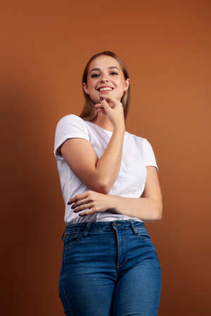 young pretty girl with blond hair posing cheerful on brown background, lifestyle people concept