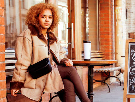 young pretty african american women drinking coffee outside, lifestyle people concept