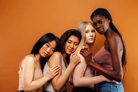 young pretty asian, caucasian, afro woman posing cheerful together on brown background, lifestyle diverse nationality people conceptの写真素材