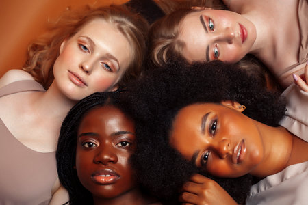 young pretty caucasian, afro, scandinavian woman posing cheerful together on brown background, lifestyle diverse nationality people conceptの写真素材