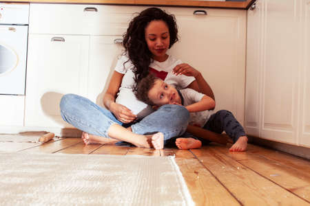 young pretty african american mother with little cute son on kitchen in morning preparing breakfast, lifestyle people conceptの写真素材