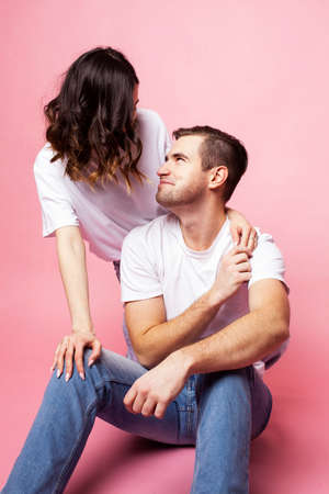 young cheerful caucasian couple together having fun on pink background, guy ang girl modern...