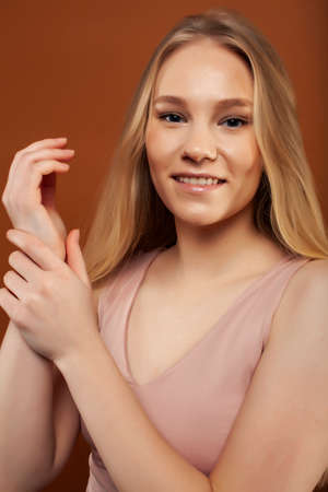 young pretty girl with blond hair posing cheerful on brown background, lifestyle people concept