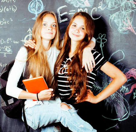 back to school after summer vacations, two teen real girls in classroom with blackboard painted...