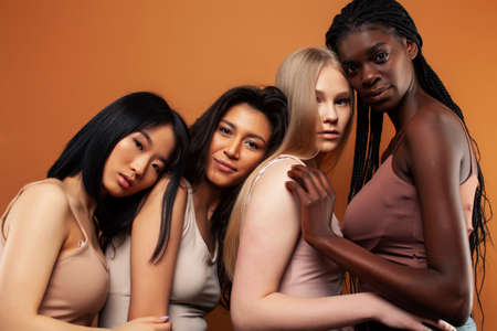 young pretty asian, caucasian, afro woman posing cheerful together on brown background, lifestyle...