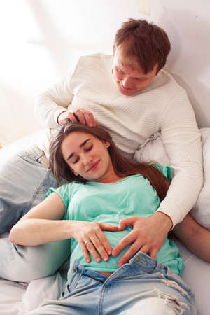 young caucasian pregnant couple together at home relaxing in bed, lifestyle people concept