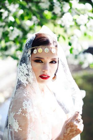 young pretty indian girl in jewelry and veil posing cheerful happy smiling in green park, lifestyle people conceptの写真素材