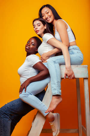 diverse multi nation girls group, teenage friends company cheerful having fun, happy smiling, cute posing on yellow background, lifestyle people concept, african-american, asian and caucasianの写真素材