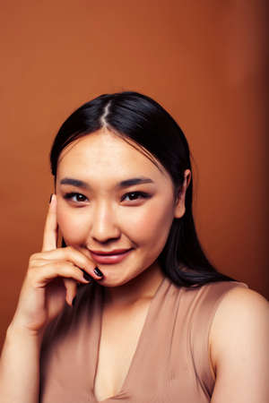 young pretty asian woman cheerful smiling posing on warm brown background, lifestyle people conceptの写真素材