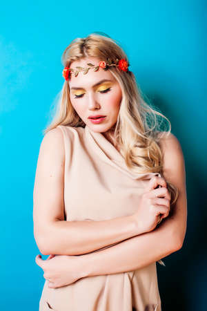 young pretty blond girl with curly blond hair and little lowers happy smiling on blue sky background, lifestyle people conceptの写真素材