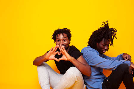 two african american guys posing cheerful together on yellow background, lifestyle people conceptの写真素材
