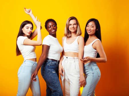 diverse multi nation girls group, teenage friends company cheerful having fun, happy smiling, cute posing on yellow background, lifestyle people concept, african-american, asian and caucasianの写真素材