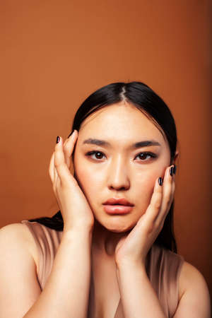 young pretty asian woman cheerful smiling posing on warm brown background, lifestyle people conceptの写真素材
