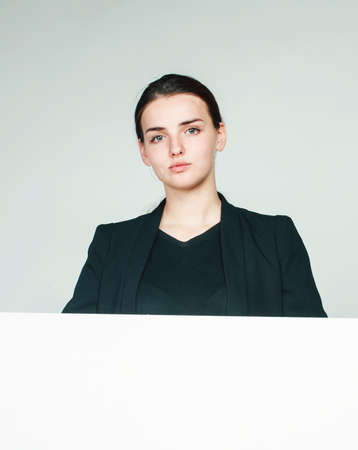 young pretty brunette girl with placard shit copyspace on white background wearing business costume studentの写真素材