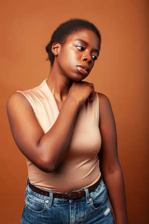 pretty young african american woman with curly hair posing cheerful gesturing on brown background, lifestyle people conceptの写真素材