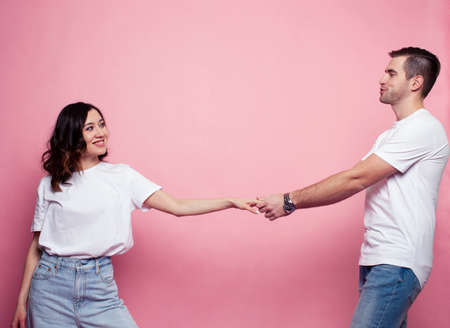 young cheerful caucasian couple together having fun on pink background, guy ang girl modern...