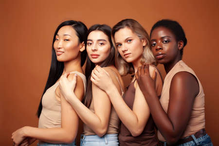 young pretty caucasian, afro, scandinavian woman posing cheerful together on brown background, lifestyle diverse nationality people conceptの写真素材