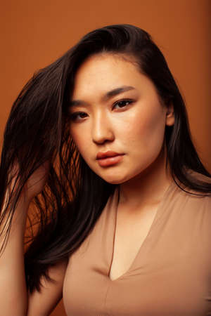 young pretty asian woman cheerful smiling posing on warm brown background, lifestyle people conceptの写真素材