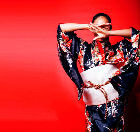 young pretty geisha on red background posing in kimono, orientalの写真素材