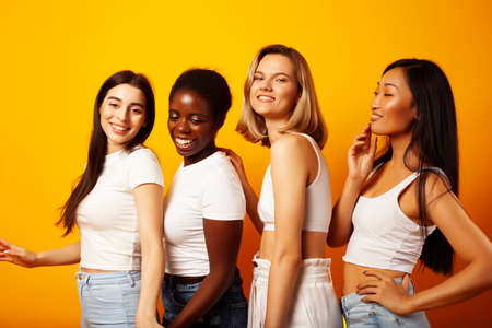 diverse multi nation girls group, teenage friends company cheerful having fun, happy smiling, cute posing on yellow background, lifestyle people concept, african-american, asian and caucasianの写真素材