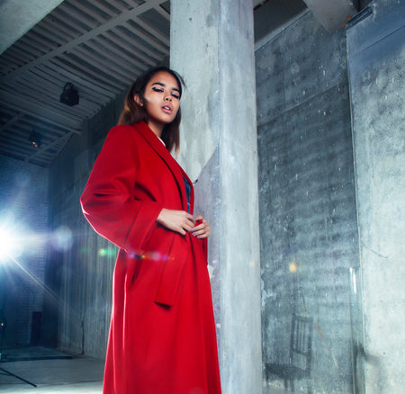young pretty african american woman in luxury red coat posing fashionable on empty parking building, lifestyle rich people conceptの写真素材