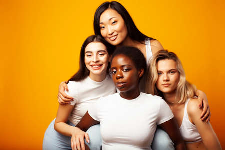 diverse multi nation girls group, teenage friends company cheerful having fun, happy smiling, cute posing on yellow background, lifestyle people concept, african-american, asian and caucasianの写真素材