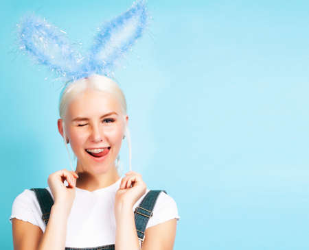young pretty blond girl with rabbit ears posing cheerful on blue background, lifestyle people conceptの写真素材