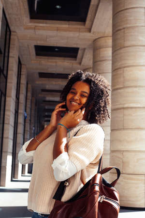 young pretty african girl posing cheerful on city background, lifestyle outdoor people concept