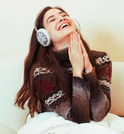 young pretty woman sitting in comfortable chair with coffee and blanket, winter season lifestyle people conceptの写真素材