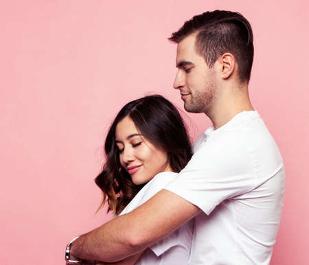 young cheerful caucasian couple together having fun on pink background, guy ang girl modern...