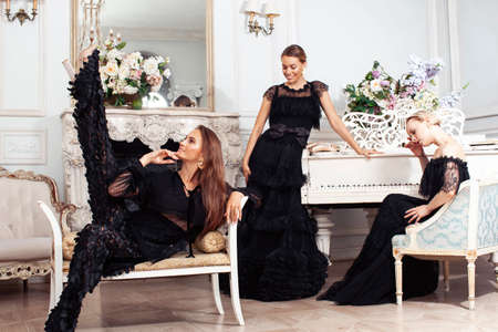 three young pretty lady in black lace fashion style dress posing in rich interior of royal hotel room, luxury lifestyle people conceptの写真素材