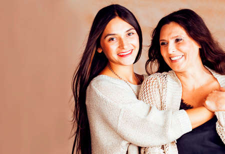 cute pretty teen daughter with mature mother hugging, fashion style brunette makeup close up tann s...