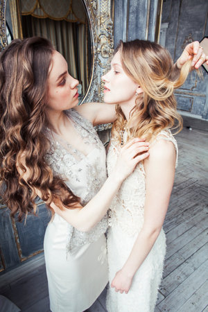 two pretty twin sister blond curly hairstyle girl in luxury house interior together, rich young people conceptの写真素材