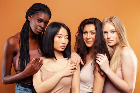 young pretty asian, caucasian, african woman posing cheerful together on brown background, lifestyle diverse nationality people conceptの写真素材