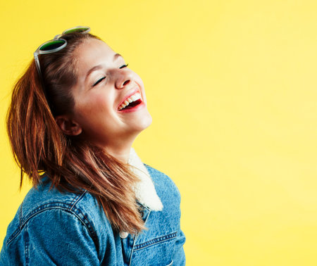 lifestyle people concept: pretty young school teenage girl having fun happy smiling on yellow backgroundの写真素材