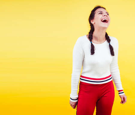 lifestyle people concept: pretty young school teenage girl having fun happy smiling on yellow backgroundの写真素材