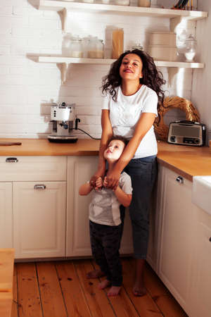 young pretty african american mother with little cute son on kitchen in morning preparing breakfast, lifestyle people conceptの写真素材