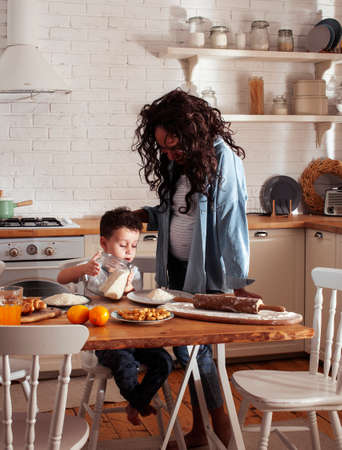 young pretty african american mother with little cute son on kitchen in morning preparing breakfast, lifestyle people conceptの写真素材