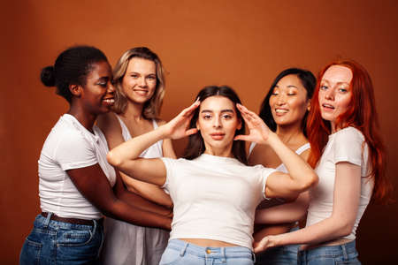 young pretty african and caucasian women posing cheerful together on brown background, lifestyle diverse nationality people conceptの写真素材
