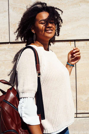young pretty african girl posing cheerful on city background, lifestyle outdoor people concept