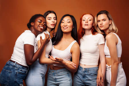 young pretty african and caucasian women posing cheerful together on brown background, lifestyle diverse nationality people conceptの写真素材