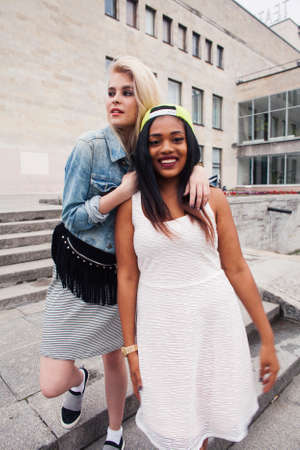Two teenage diverse nations girls infront of university building smiling, having fun traveling europe, lifestyle people conceptの写真素材