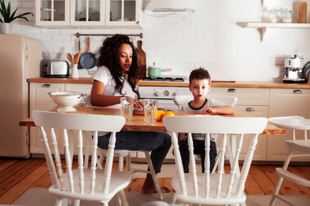 young pretty african american mother with little cute son on kitchen in morning preparing breakfast, lifestyle people conceptの写真素材