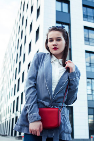 young pretty brunette business woman posing emotional against modern building in glasses holding coffee, lifestyle people conceptの写真素材